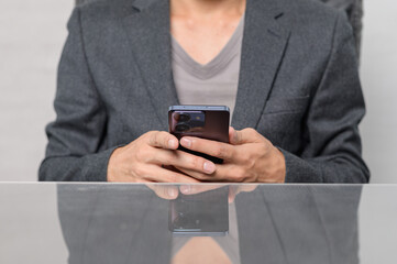 Person using smartphone while seated at table in modern office