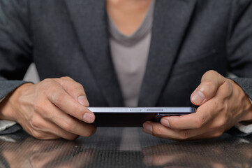 Businessman Holding Smartphone in Formal Attire at Modern Workspace