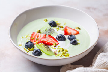 Green matcha yogurt with berries and pistachio. Vegan breakfast concept.