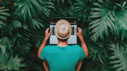 A person in a green shirt and hat works on a laptop surrounded by lush tropical foliage, highlighting a blend of technology and nature.