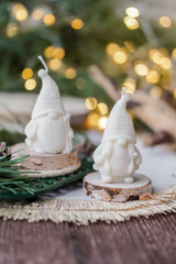 Beautiful soy wax candles in the room, decorated with fir tree branches, Christmas lights in the backgound