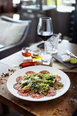 Beef carpaccio. Borettane onion, sun-dried tomato, truffle dressing, arugula salad, parmesan cheese. Italian traditional antipasti snacks served for lunch with wine in modern gourmet restaurant