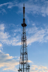 A Tall Telecommunication Tower Stands Out Against A Vibrant Blue Sky With Scattered White Clouds. 