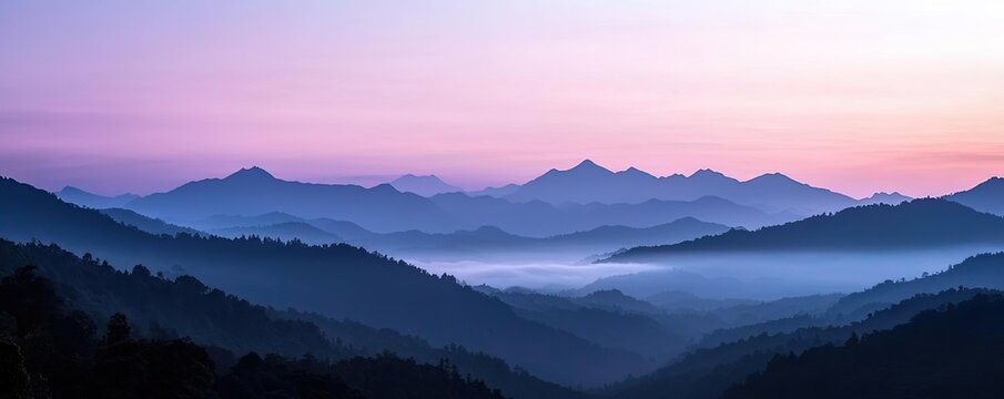 Misty mountain nature idea. Stunning panoramic view of misty mountains at dusk, with soft pastel colors in the sky.