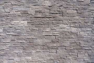 A detailed view of a modern gray stone wall with rectangular patterns and rough texture.