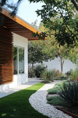 Obraz premium This contemporary home showcases a stunning modern garden design, complete with a charming winding stone path enveloped by vibrant greenery, all illuminated by the bright daylight