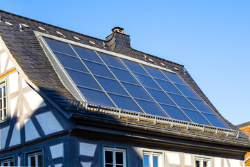 Solar panels installed on a sloped slate roof, providing sustainable energy for a house