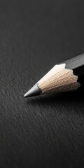 Close-up of a sharpened pencil tip on a dark surface, ideal for creative projects and educational materials.