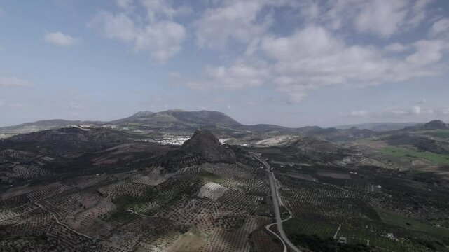 Aerial 4K footage of Olvera, Spain, captured with a DJI drone at 30fps. A cinematic view of open meadows with a stunning castle atop the mountain in the background.