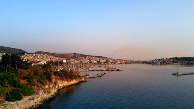 Wide aerial shot of the port of Mytilene, Lesbos, Greece, featuring boats and the glow of orange sunlight.