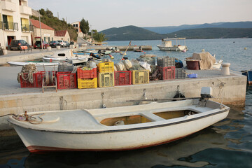 A picturesque harbor during sunset, with fishing boats docked by stone Medieval houses and fishing...