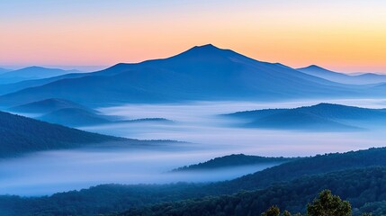 Fototapeta premium Misty mountain nature idea. Stunning mountain range with mist and colorful sunrise creating a peaceful atmosphere.