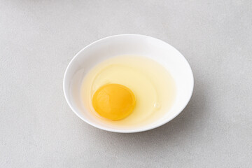 Raw egg in white bowl