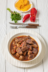 beef stew in a white bowl on rustic wooden table