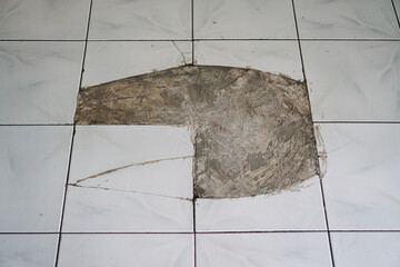 Close-up view of damaged floor tiles showing cracks and missing pieces. Needs repair or...