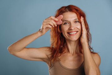 Pink colored face patch being used on the skin. Woman is in the studio against background