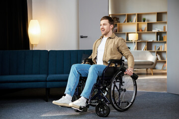 Obraz premium Physical rehabilitation for disabled people. Happy guy in wheelchair making exercises with dumbbell at home. Cheerful impaired young man working out with weights indoors