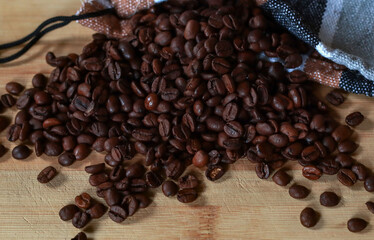 Still life. Coffee beans spilled out of the bag onto a wooden board. Close-up. Copyspace