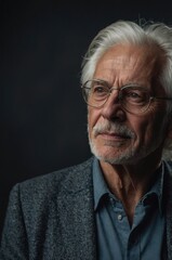 Obraz premium Elderly man with silver hair and glasses looks thoughtfully, showcasing wisdom and experience