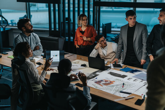 A diverse group of business people engaged in a brainstorming session. They are working together on a project, showcasing teamwork and innovative thinking in a modern office environment.
