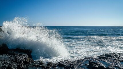 Fototapeta premium Ocean waves crashing on rocks, creating white spray against blue sky