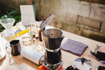 classic Moka pot brews espresso over a portable on gas stove releasing fresh coffee aroma perfect outdoors brewing experience blending tradition, simplicity and barista style craftsmanship.