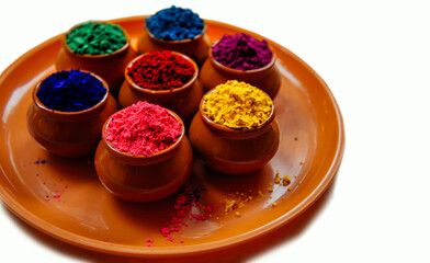 Colorful Holi powder in cups on a tray closeup. Bright colours for Indian holi festival in clay pots. Selective focus