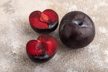 Purple Plum Cut in half on brown concrete, Side view, close up