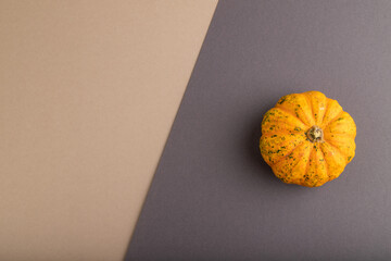 Orange Pumpkin on beige and gray pastel paper. Top view, copy space