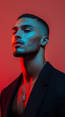 A young man exudes charisma and confidence, illuminated by vivid red and blue lighting in a contemporary environment. His stylish attire and thoughtful gaze add depth to the artistic composition