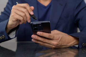 Man Using Smartphone with Pen in Modern Business Setting