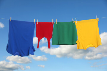 Different clothes drying on washing line against blue sky
