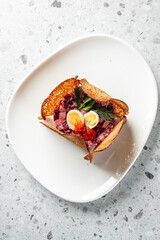 A creative dish featuring a vibrant salad nestled in a crispy bread bowl. Topped with halves of quail eggs, fresh herbs, and red caviar, it offers a unique visual appeal