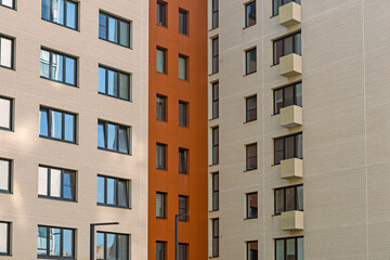 Architectural detail of residential building featuring beige and orange sections with multiple windows