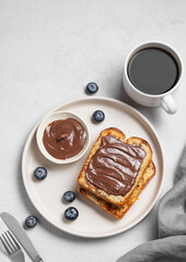 Toasted bread with chocolate cream on  a plate on a light  background with a cup of espresso coffee