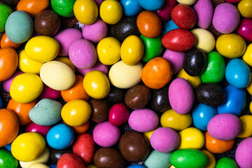 Colorful candy eggs scattered. Brightly colored candy eggs in various sizes and hues create a vibrant display on a textured surface, evoking joy.