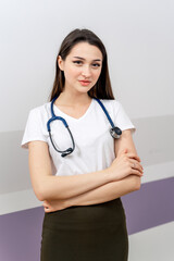 Young woman with stethoscope. Confident young woman wearing a stethoscope stands with arms crossed, showcasing commitment to healthcare.