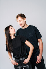 Casual couple smiling for photos. A couple enjoys a playful moment, smiling and posing together in stylish casual outfits against a neutral backdrop.