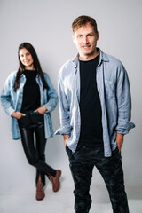 Young adults in casual outfits. Two young adults stand against a neutral background, smiling confidently in trendy outfits during a photoshoot.