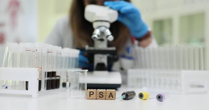 In a laboratory setting, a microscope is used for detailed analysis of blood samples along with PSA test tubes