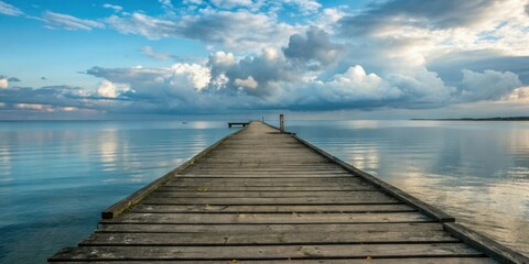 Obraz premium Wooden pier extending into calm water under a dramatic sky