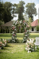 Wedding ceremony. Very beautiful and stylish wedding arch, decorated with various fresh flowers, standing in the garden.