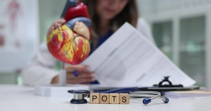 A medical professional studies Postural Orthostatic Tachycardia Syndrome POTS using a heart model and notes