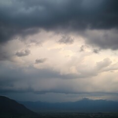 Dramatic cloud formations gather over a mountain landscape at dusk, hinting at an impending storm
