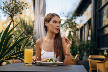 Delicious food. Beautiful young woman is outdoors of the restaurant by the table