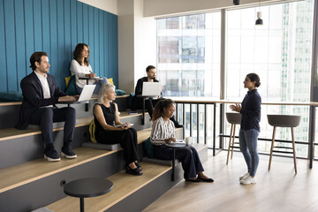 Indian female speaker talking to multiethnic corporate staff members, giving knowledge and new...