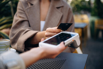 Woman is paying for food in cafe by using credit card. Conception of wireless money transfer