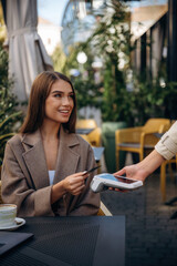 Positive, cheerful facial expression. Woman is paying for food in cafe by using credit card....