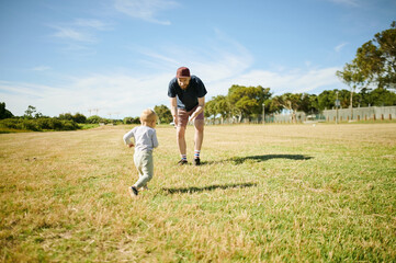 Naklejka premium Park, happy and baby play with father in field for bonding, quality time and adventure in countryside. Family, love and boy with dad relax outdoors on holiday, summer vacation and weekend in nature