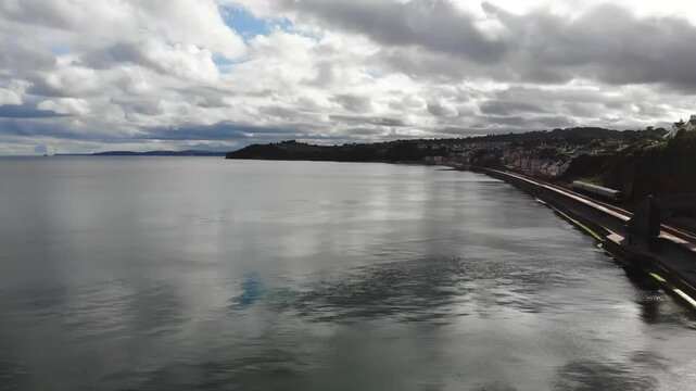 Coastline aerial view showcasing seawall, tranquil waters, and distinctive geography of Dawlish, Devon. rising shot